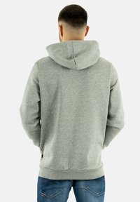 Gray hoodie with a textured finish, featuring a hood, front pockets, and ribbed cuffs, paired with blue jeans. Back view is shown.