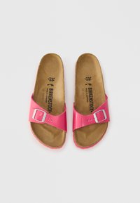 Roze Birkenstock-sandalen met een glanzend synthetisch bovenwerk, verstelbare gesp en een bruin, gevormd kurken voetbed met een gestructureerde zool.