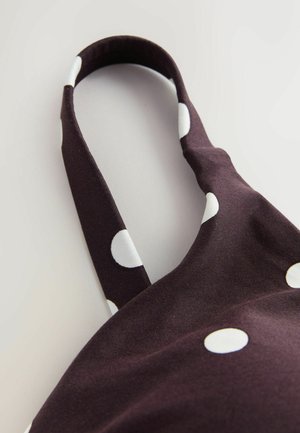 Tessuto viola scuro con pois bianchi. Include una fascia curva. Texture liscia, che mette in risalto un design casual. L'inquadratura ravvicinata evidenzia i dettagli.