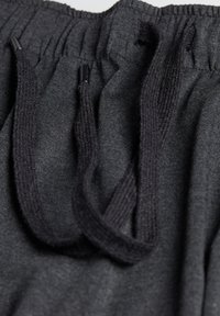 Grå sweatpants har ett texturerat tyg med en mjuk finish, ett elastiskt midjeband och svarta snören för justering.