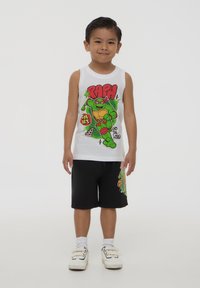 Canottiera bianca senza maniche con un personaggio di cartone animato verde con accenti rossi e testo grafico. Pantaloni corti neri con un design del personaggio simile.