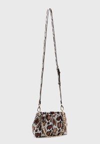 Bolso de hombro con estampado animal marrón y blanco, con acabado texturizado, acento de cadena dorada y correa ajustable. Forma compacta y curva.