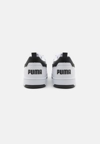 Lærsneakers med et hovedsakelig hvitt skinn, svart hæl og detaljer, med en fremtredende 'PUMA'-logo bak og en teksturert såle.