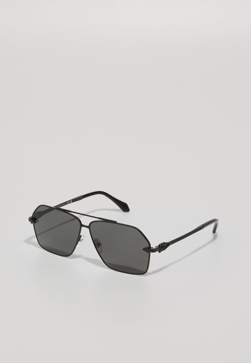 Lunettes de soleil noir en métal avec des verres octogonaux, teinte grise et branches texturées. Équipées de plaquettes de nez ajustables et de branches fines et élégantes.