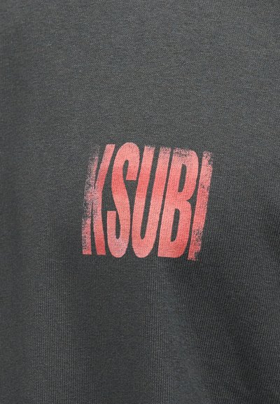 Γκρι βαμβακερό μπλουζάκι με ανάγλυφο, φθαρμένο κόκκινο γραφικό λογότυπο που γράφει "KSUBI" στο μπροστινό μέρος. Κοντά μανίκια και στρογγυλή λαιμόκοψη.