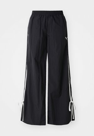 Fekete, bő lax elejű nadrág, könnyű anyagból készült, húzózsinóros záródással, fehér oldalcsíkokkal és zsinórral a szegélyén.