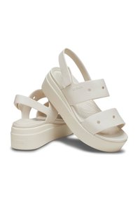 White platform sandals with two wide straps and adjustable back strap, made of flexible material, featuring a textured footbed and rounded shape.