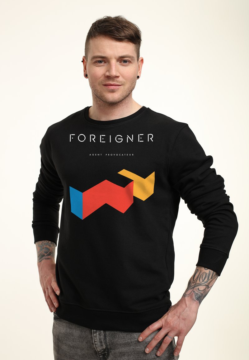Felpa nera con stampa grafica in rosso, blu, giallo e bianco con il testo "FOREIGNER" e "AGENT PROVOCATEUR." Maniche con polsini a costine.