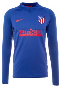 Sininen pitkähihainen urheilu paita, jossa on neljännesvetoketju kauluksessa. Edessä on punainen Nike-logo ja "Plus500"-sponsorointi punaisella tekstillä.