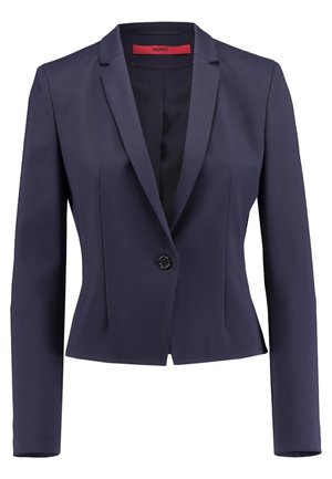 Granatowa dopasowana damska marynarka z długimi rękawami, pojedynczym czarnym guzikiem i czerwoną wewnętrzną metką.