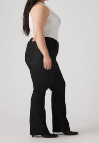 Jeans negros acampanados con tiro medio, que cuentan con bolsillos delanteros y traseros, costuras en contraste y una etiqueta de cuero en la cintura.