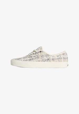 Alacsony szárú Vans sportcipő krémszínű texturált anyagból, fehér talppal, fehér fűzőkkel és kis Vans logóval az oldalon, a fűzők mellett.