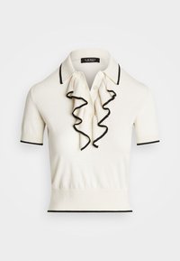 Polo couleur crème avec un devant à volants, des accents noirs sur le col et les manches, manches courtes, et une taille ajustée. Confectionné en matière tricotée douce.