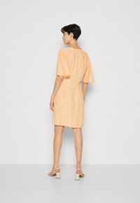 Robe florale courte orange avec des manches courtes évasées et une coupe décontractée, présentant un simple col au dos et une texture de tissu lisse.