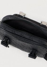 Borsa a spalla nera con texture, motivo logomarca in rilievo, hardware in argento, chiusura con zip e spallacci regolabili. L'interno presenta una fodera liscia.