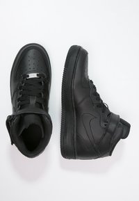 Czarne wysokie trampki wykonane ze skóry, z perforacjami na palcach, z zawiązywanym zapięciem, wyściełanym kołnierzem oraz teksturowaną gumową podeszwą.