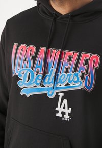 Sweat à capuche noir avec "LOS ANGELES" en rouge et "Dodgers" en bleu clair sur la poitrine, avec un logo "LA" blanc en bas.