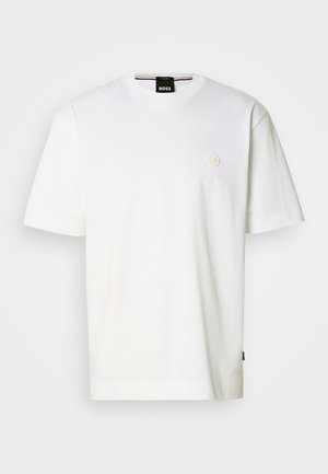 T-shirt branca de algodão com decote redondo, mangas curtas e pequeno logótipo no peito. Bainha inferior com corte recto.