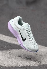 Chaussure de course Nike avec un dessus en maille bleu clair, un swoosh noir et une semelle extérieure violette. Comprend un col rembourré et un design à lacets.