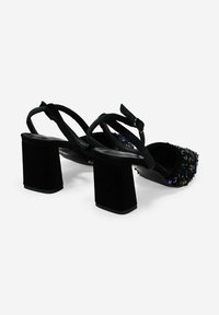 Sandalias negras de tacón con parte superior de tela texturizada con lentejuelas, tacones cuadrados anchos y tiras cruzadas en el tobillo.