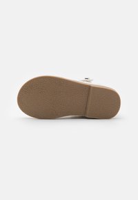 White shoe sole with textured brown rubber, featuring a slight heel and a raised section for added grip. Minimal design with no visible accents.