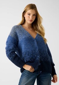 Blauwe gebreide cardigan met een verloopkleur, V-hals en blauwe knopen. Gemaakt van zacht, gestructureerd materiaal met een comfortabele pasvorm.