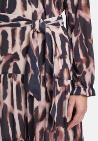 Luftiges Kleid aus leichtem Stoff mit einem rosa und dunkelbraunen Tierdruck. Tailliert mit einem gebundenen Gürtel. Lange Ärmel mit gerafften Manschetten.