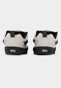 Λευκά σουέντ αθλητικά παπούτσια με μαύρες λεπτομέρειες, σχεδιασμένα με λογότυπο στη φτέρνα, στρογγυλή μύτη και υφασμένο μαύρο καουτσούκ στην σόλα.