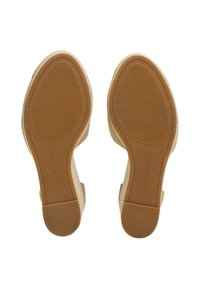 Beige Keilabsätze mit einem strukturierten Stoffobermaterial und einer glatten Gummisohle, ausgestattet mit einem geriffelten Muster für besseren Halt und geprägtem Branding.