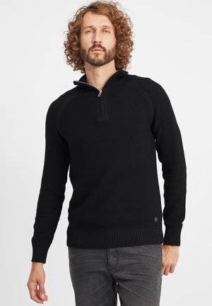 Jersey negro de punto con cuello con cremallera estilo simulado, puños y dobladillo acanalados, patrón texturizado y un detalle de logo en la parte inferior izquierda.