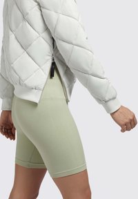 Light gray puffer jacket with quilted design and zippered side, paired with light green ribbed shorts featuring a snug fit and hemmed cuffs.