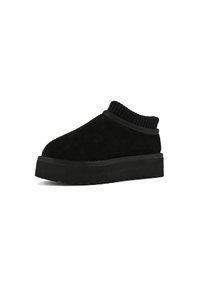 Svart mocka slip-on sko med ribbad mudd och tjock, texturerad sula, med rund tå och minimalistisk design.