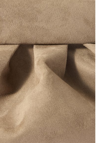 Tessuto scamosciato beige con una texture morbida e visibile e pieghe naturali che creano dolci ombre.