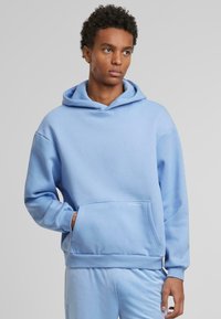 Felpa con cappuccio blu chiaro realizzata in tessuto morbido, con tasca frontale e polsini a costine, dal design minimalista.