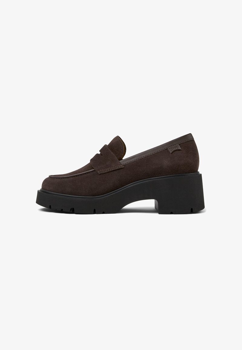 Brown suede loafers with a flat, ridged black platform sole, featuring a rounded toe and a decorative strap across the upper.