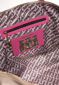 Juicy Couture Handtasche Innenseite mit einer pinken Reißverschlusstasche und Logo-Patch, ausgekleidet mit wiederholendem schwarzem Text auf hellem Hintergrund.