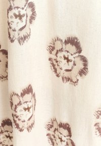 Kreemikas ja pruunides toonides lillemustriga kangas. Omab abstraktse lillekujundusega pehmet tekstuuri ja kerget välimust.