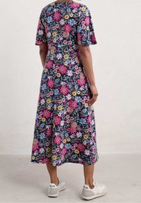 Robe midi à motif floral avec un fond bleu marine, des manches courtes et une coupe décontractée. Portée avec des baskets blanches.