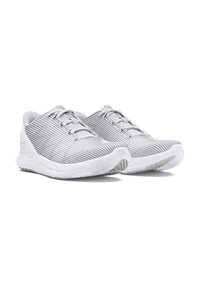 Weiße Sportschuhe mit einem strukturierten Streifen-Obermaterial, flachen Schnürsenkeln und einem gepolsterten Kragen. Die Sohle ist dick und hat ein gemustertes Profil für besseren Halt.