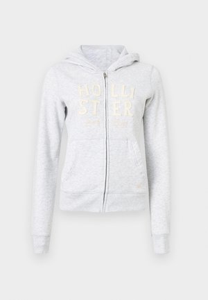 Felpa zipata grigia chiaro con cappuccio, tasche frontali e ricamo in crema "HOLLISTER Surf Club" sul petto.