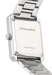 Πίσω μέρος ασημί ορθογώνιου ρολογιού χειρός με μεταλλικό μπρασελέ και χάραξη "Commonlines" και "Ο χρόνος είναι χρήμα."