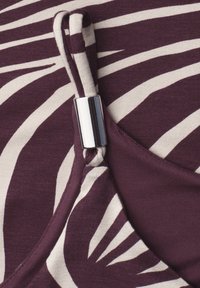 Purple and white abstract patterned fabric with a looped strap held by a shiny silver metal clasp.