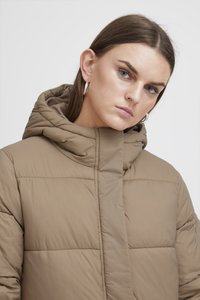 Veste à capuche en taupe, dotée d'un design matelassé, d'un col haut et d'une capuche. Texture lisse avec des détails de couture visibles et une fermeture à l'avant.