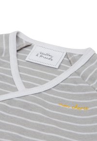 Gray and white striped fabric with a v-neck design. Features a white trim and yellow embroidered text reading "mon chéri." Brand label visible.