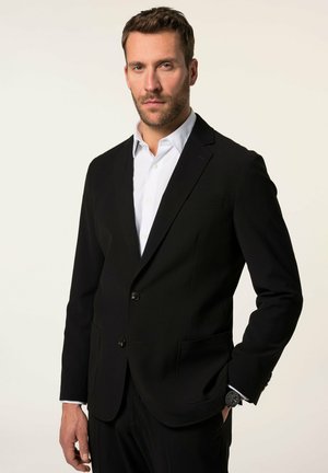 Schwarzer taillierter Blazer mit zwei Fronttaschen, einem Ein-Knopf-Verschluss und schlanker Passform. Getragen über einem weißen Hemd mit Kragen, dazu eine Uhr am Handgelenk.