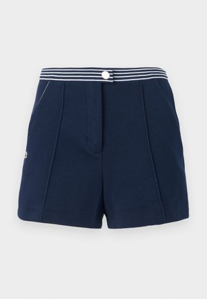 Shorts bleu marine avec ceinture rayée, fermeture à bouton et poches latérales, présentant un tissu subtilement texturé et un petit logo sur le côté gauche.