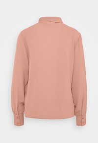 Blusa a maniche lunghe in morbido tessuto rosa. Presenta un colletto, polsini con bottoni e una linea dritta con una texture liscia.