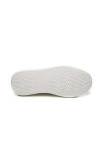 Sole di scarpa in gomma bianca con un motivo di grip testurizzato, caratterizzata da forme geometriche in rilievo e un bordo liscio, identificabile da un'etichetta di marca discreta.