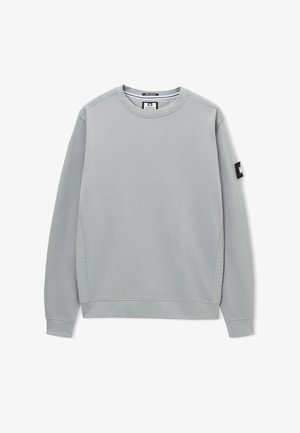 Hellgraues Sweatshirt mit langen Ärmeln und Rundhalsausschnitt, mit gerippten Bündchen, gesteppte Schulter- und Seitendetails sowie einem schwarzen rechteckigen Aufnäher am linken Ärmel.