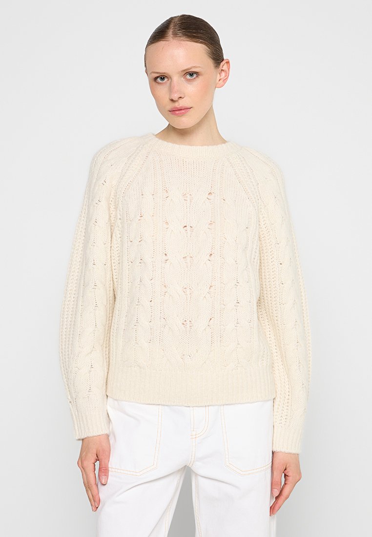 Cremfarbener, gestrickter Pullover mit Zopfmuster, gerippten Bündchen und Saum sowie einem lässigen Schnitt. Die Kombination mit weißen Hosen vervollständigt den Look.
